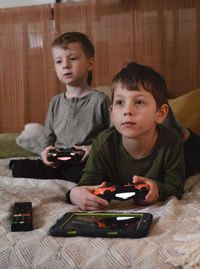 Kids playing video games at home on the bed at night. boys using game console and having fun in the