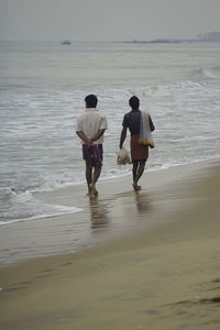 Rear view of people walking on beach