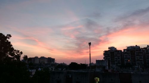 Silhouette of city against cloudy sky during sunset