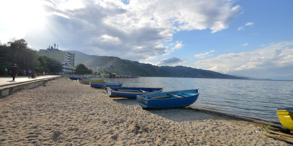 Boats moored on shore against sky