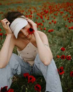 Side view of young woman looking away while sitting on field