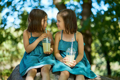 Two little girls drinking lemonade in park