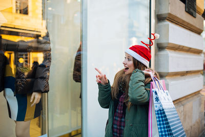 Surprised woman pointing window display of store in city