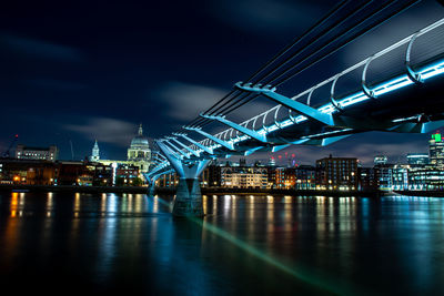 Illuminated bridge over river against sky at night