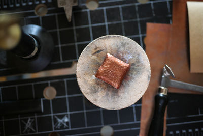 A metal plate made of copper with a pattern, with tools on a workbench, a workpiece for decorating 
