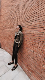 Full length of woman standing against wall