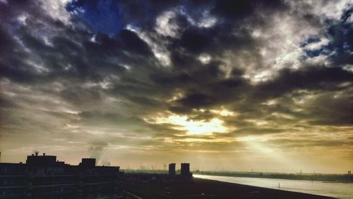 Silhouette of buildings against cloudy sky