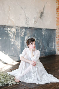 Full length of young woman sitting indoors