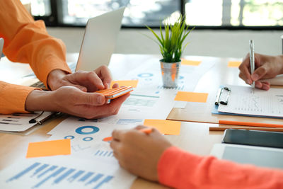 Cropped hands of business people working on desk in office