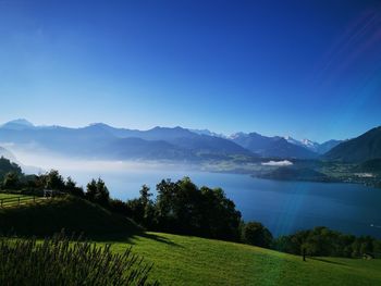 Scenic view of landscape and mountains against clear blue sky
