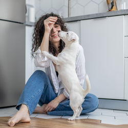 Woman with dog sitting on floor at home