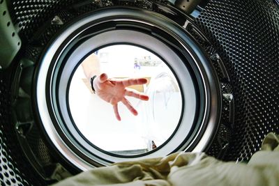 Cropped image of hand on washing machine glass