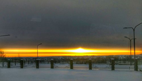 Silhouette trees on snow against sky during sunset