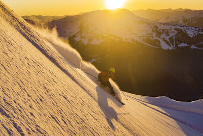 Man skiing on snow during sunset