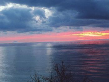 Scenic view of sea against cloudy sky at sunset