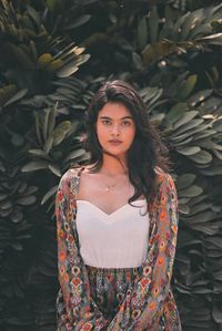 Portrait of beautiful young woman standing against wall