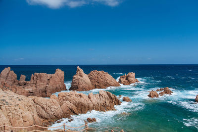 Rocks on beach against blue sky