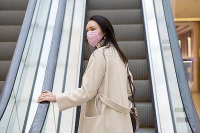 Side view of a smiling young woman standing against railing