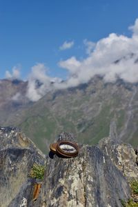 Close-up of navigational compass on rock against sky