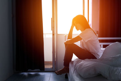 Rear view of woman sitting on floor at home