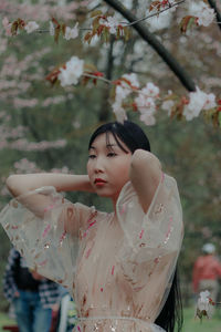 Portrait of young woman standing against trees