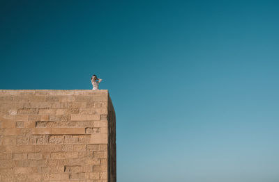 Low angle view of woman against clear blue sky