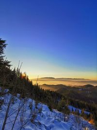 Scenic view of snowcapped landscape against clear sky during sunset