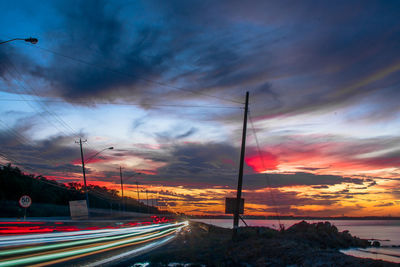 Light trails on road against sky at sunset