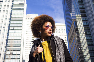 Woman standing against modern buildings in city