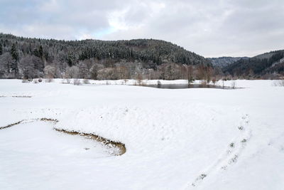 Scenic view of snow covered field against sky