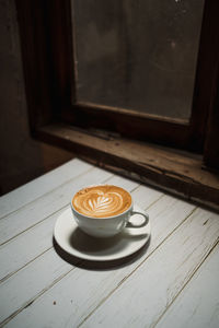 Latte art coffee on wooden table in coffee shop