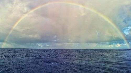 Scenic view of rainbow over sea against sky