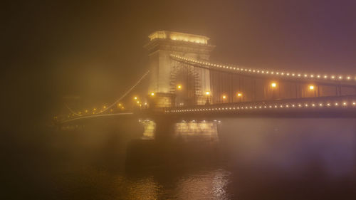 Illuminated bridge over river at night