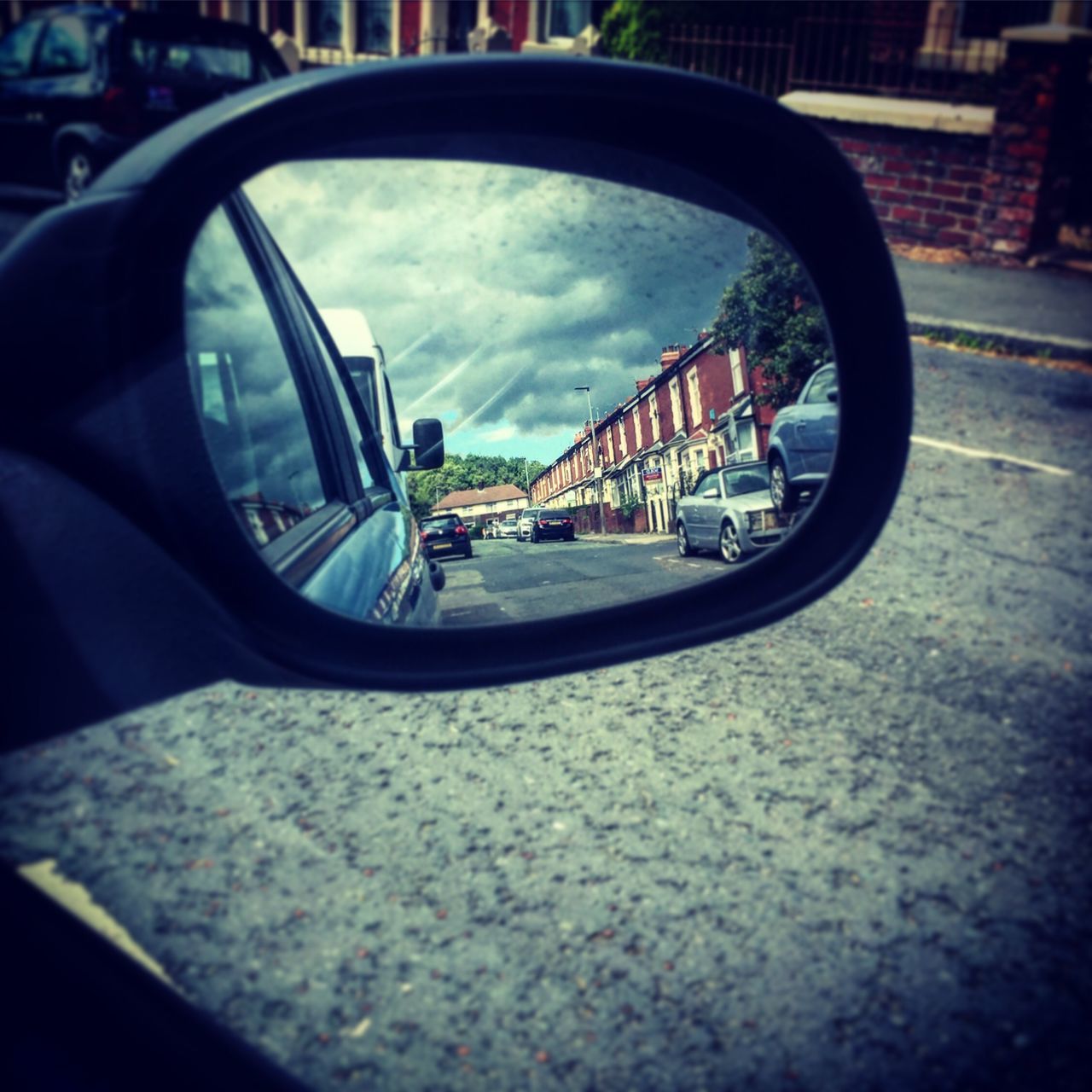 REFLECTION OF SIDE-VIEW MIRROR OF CAR ON WINDSHIELD