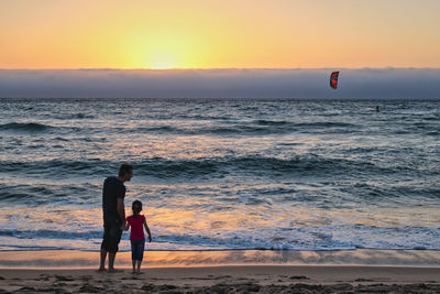 Woman on beach against sky during sunset