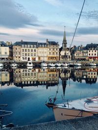 Sailboats moored in harbor against buildings in city