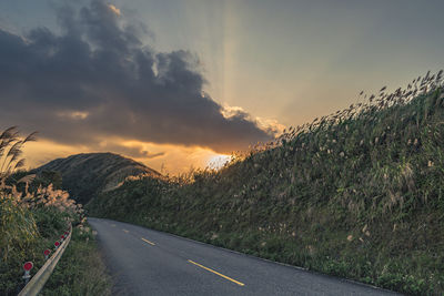 Empty road against sky during sunset