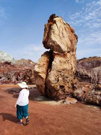 Rear view of woman standing on rock against sky