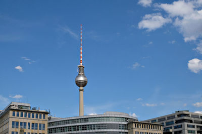 Low angle view of communications tower in city against sky