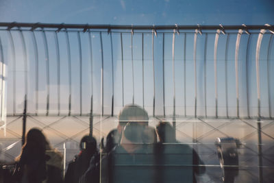 Reflection of photographer with tourists on glass window of empire state building