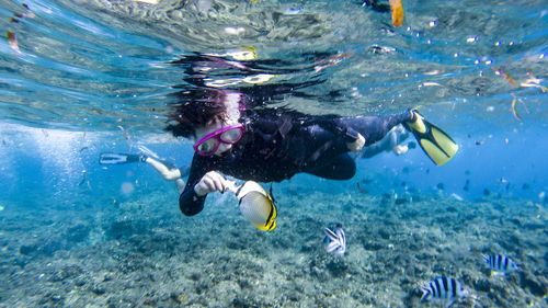 Full length side view of woman scuba diving undersea