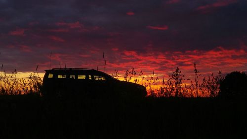 Silhouette built structure against dramatic sky during sunset