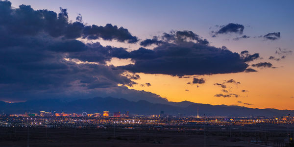 Illuminated buildings in city against sky during sunset