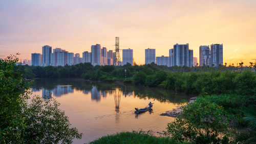Scenic view of river by buildings against sky during sunset in ho chi minh city