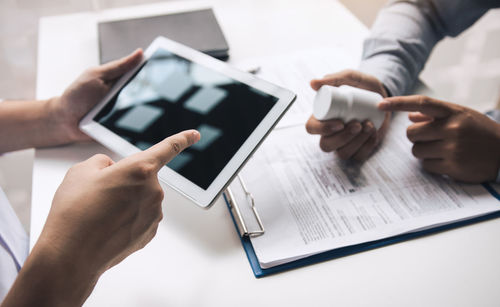 Midsection of man using smart phone on table