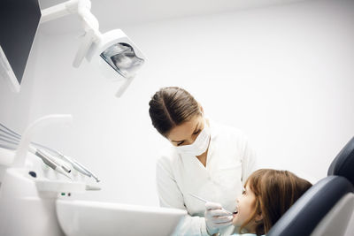 Female dentist examining girl at clinic