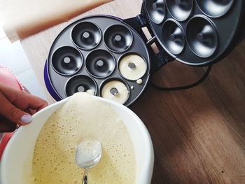 Cropped hand of woman pouring batter in container at table