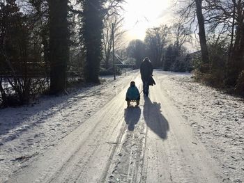 Rear view of woman walking on road in winter