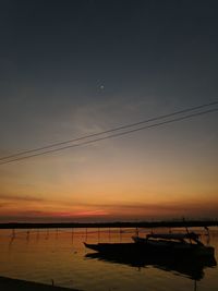 Silhouette boats moored in sea against sky during sunset