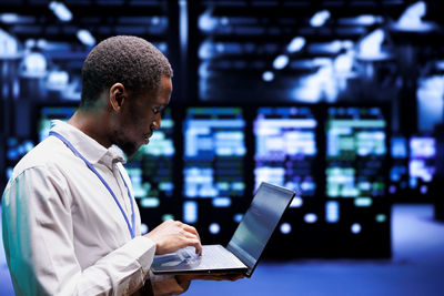 Side view of man using laptop at office